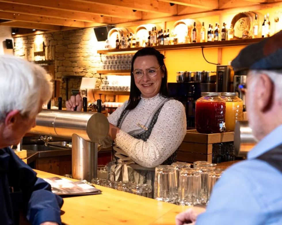 Gäste an der Bar einer Bavaria Alm